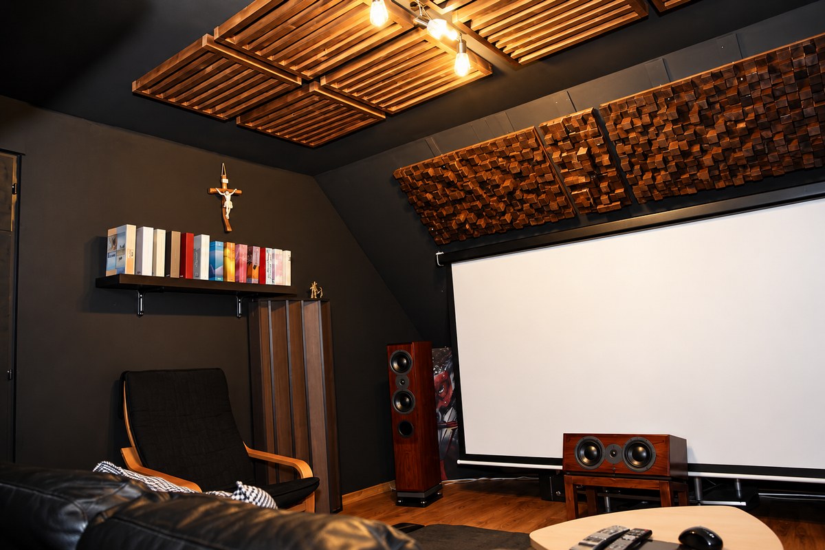 Diffusori Skyline 60x60x14 cm in una sala d’ascolto moderna, con struttura tridimensionale in legno dietro l’impianto hi-fi