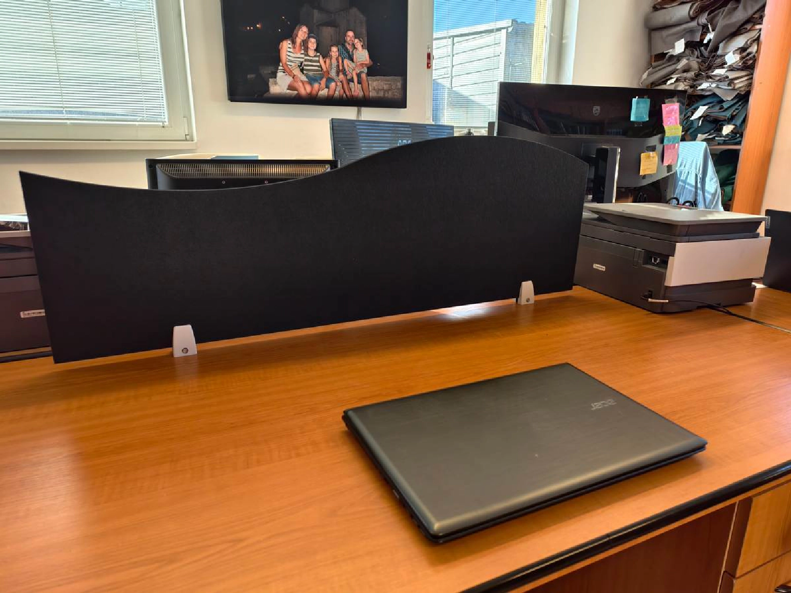 Bilnora schermo acustico Onda 1 nero montato su una scrivania da ufficio con monitor e stampante sullo sfondo.