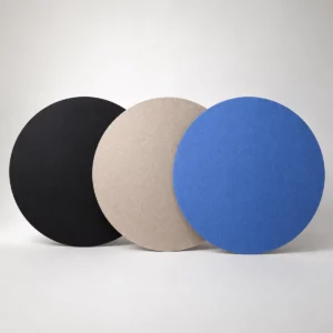 Tre pannelli da soffitto rotondi in feltro Bilnora, disposti uno accanto all’altro nei colori nero, beige e blu, con bordi netti e texture del feltro uniforme in evidenza.